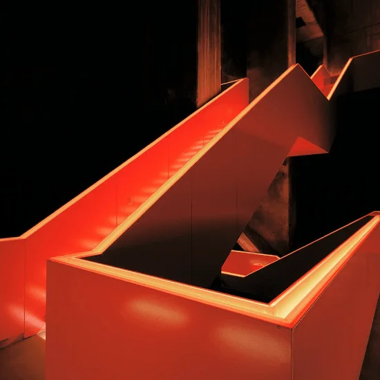 Leuchtend rote, moderne Treppe in einem dunklen Raum.